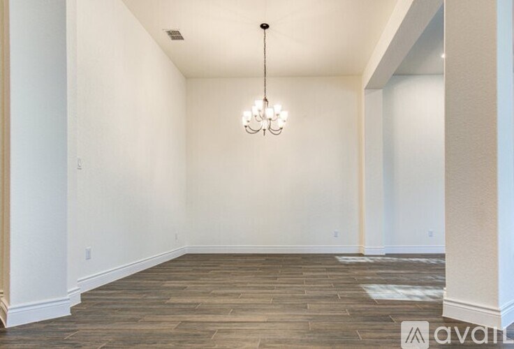 A room with wooden flooring and a chandelier hanging from the ceiling.