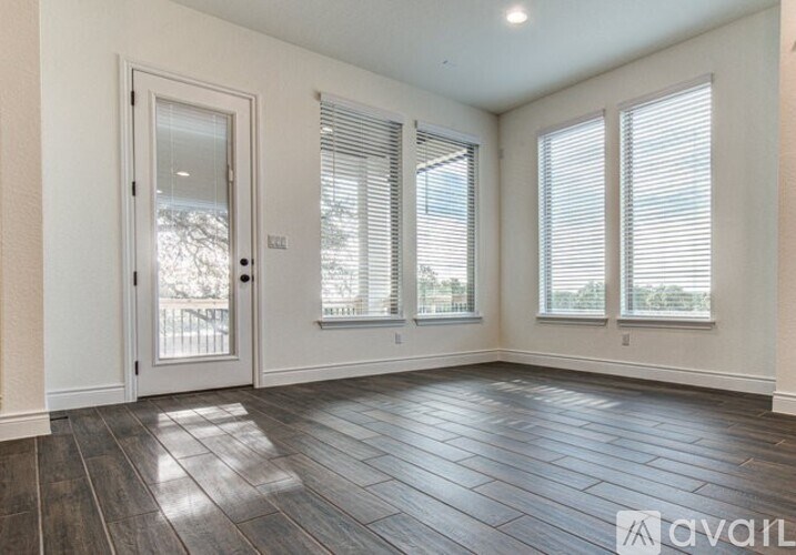 A room with a wooden floor and three windows with blinds.