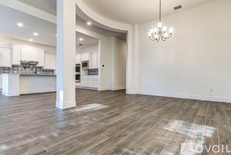 A spacious kitchen with white cabinets and a wooden floor.