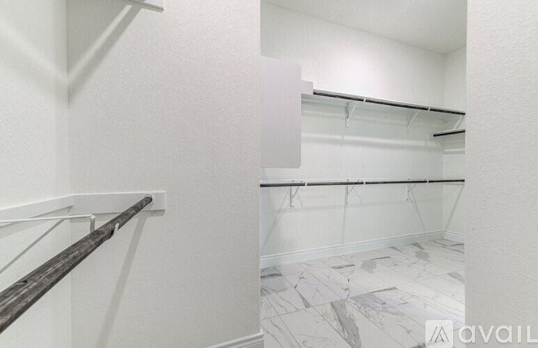 A white hallway with marble flooring and a white wall.