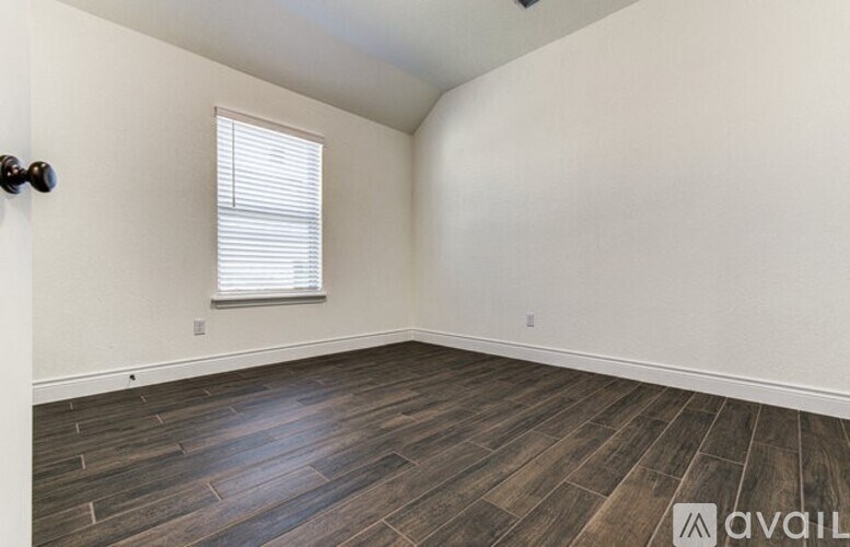 A room with wooden flooring and a window with blinds.