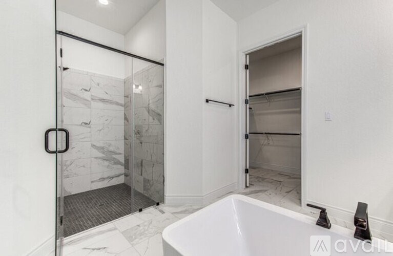 A bathroom with a marble shower and a white bathtub.
