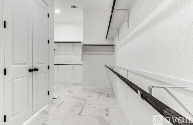 A white hallway with a marble floor and a black railing.