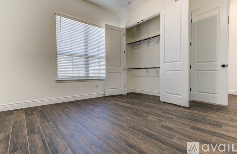 A room with a window and a wooden floor.