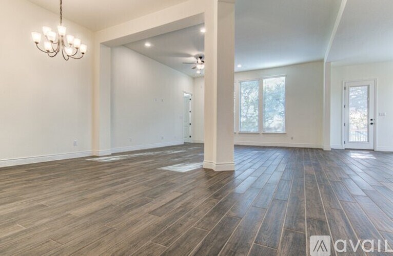 A spacious room with wooden flooring and a chandelier.