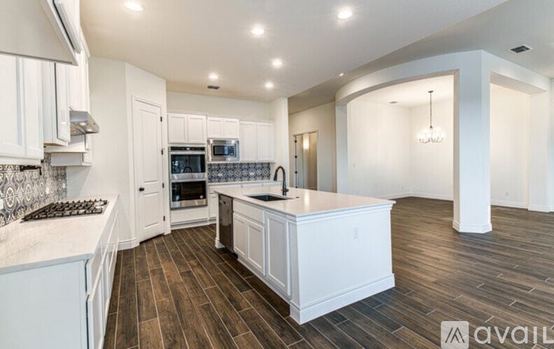 A kitchen with white cabinets and a wooden floor.