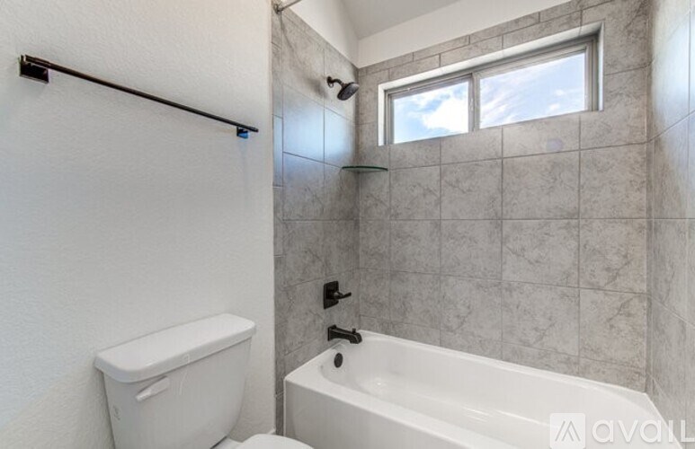 A bathroom with a white toilet, a white bathtub, and a window.