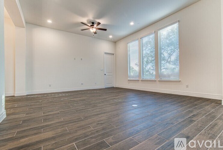 A spacious room with wooden flooring and a ceiling fan.