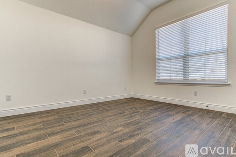 A room with wooden flooring and a window with blinds.