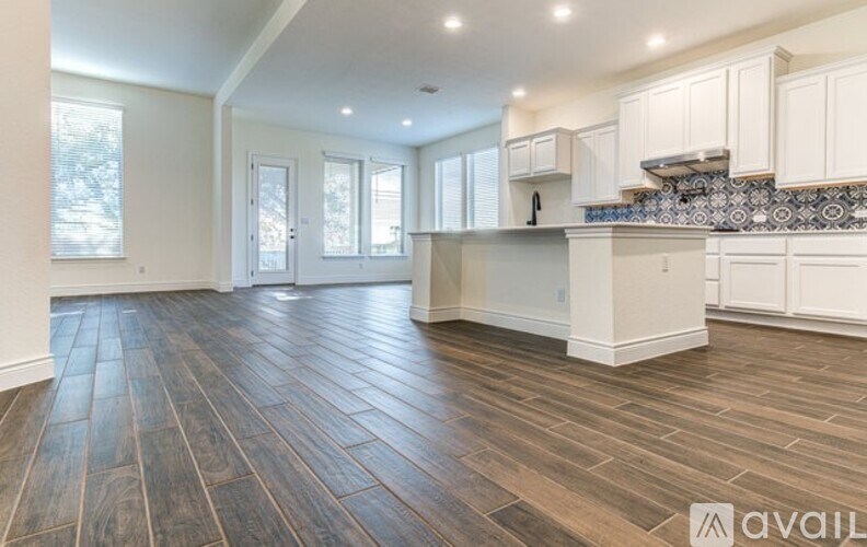 A kitchen with wooden floors and white cabinets.