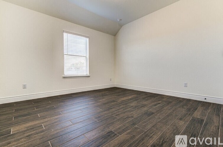 A room with wooden flooring and a window with blinds.