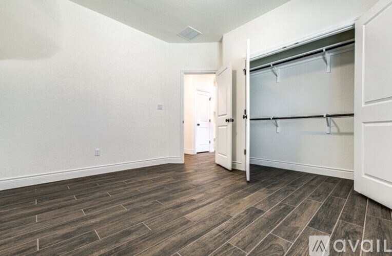 A spacious room with a wooden floor and a white wall.