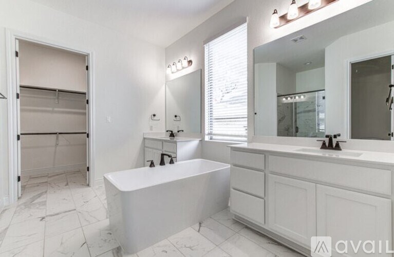 A white bathroom with a tub, sink, and mirror.