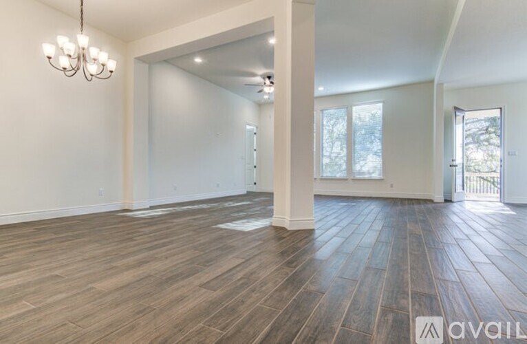 A spacious room with wooden flooring and white walls.