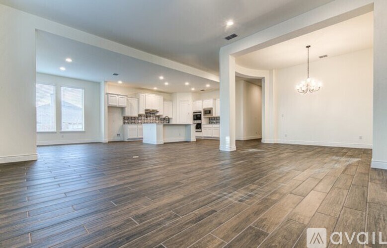 A spacious room with wooden flooring and a chandelier.