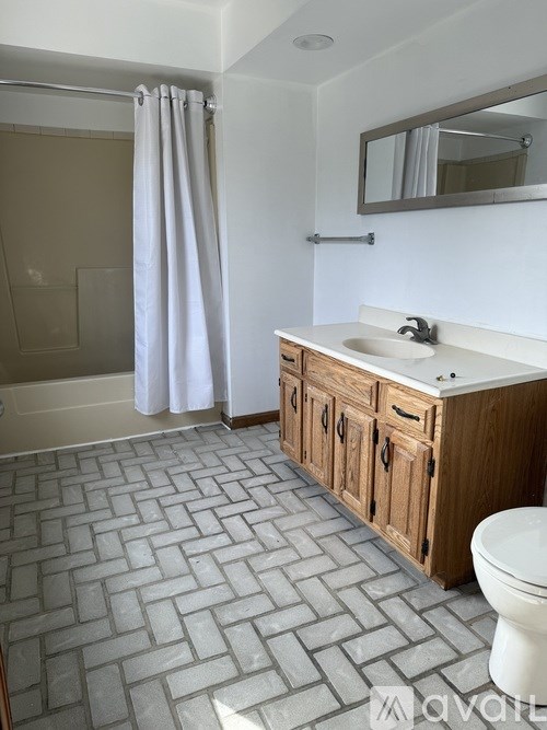 A bathroom with a white sink, wooden cabinets, and a tiled floor.