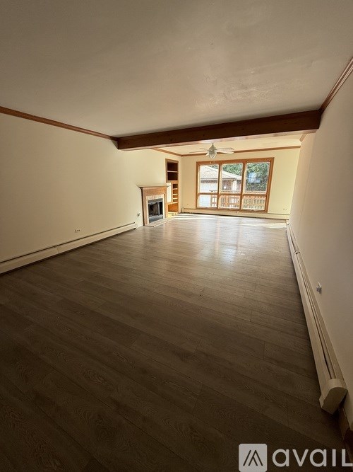 A spacious room with wooden flooring and a ceiling fan.
