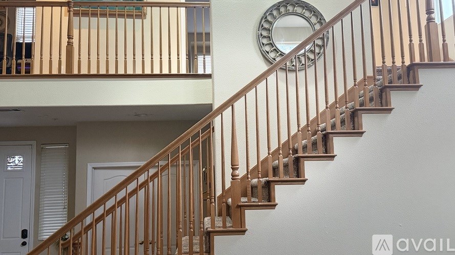 A staircase with a wooden banister and a round mirror on the wall.