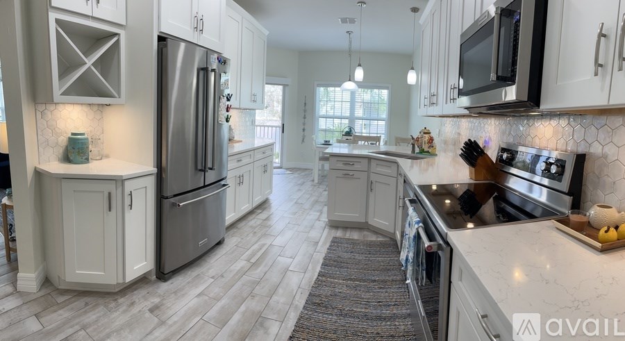 A kitchen with white cabinets and a refrigerator.