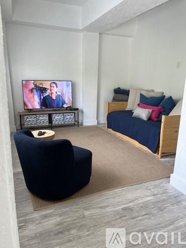 A living room with a blue chair and a bed with a blue blanket.