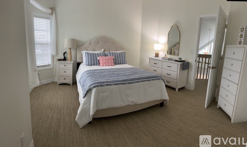 A bedroom with a large bed, a dresser, and a mirror.