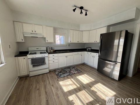 A kitchen with white cabinets and a black refrigerator.