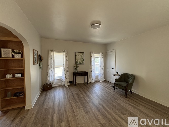 A room with wooden flooring and furniture including a chair and a table.