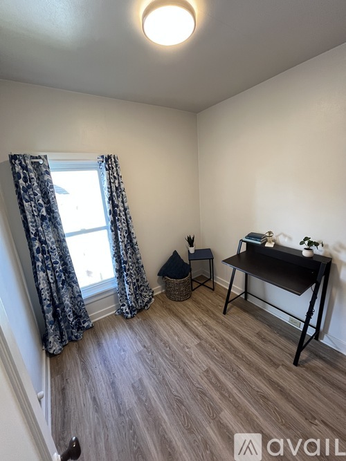 A room with a desk and chair by a window.