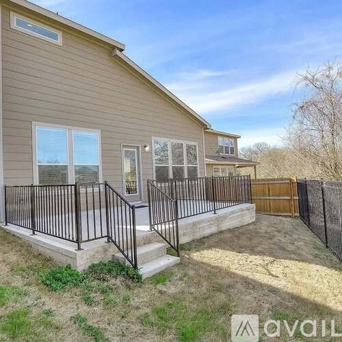 A house with a beige exterior and a black railing on the balcony.