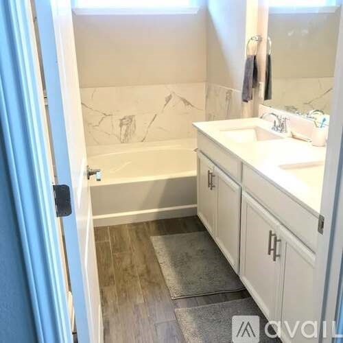 A bathroom with a marble patterned wall and a bathtub.