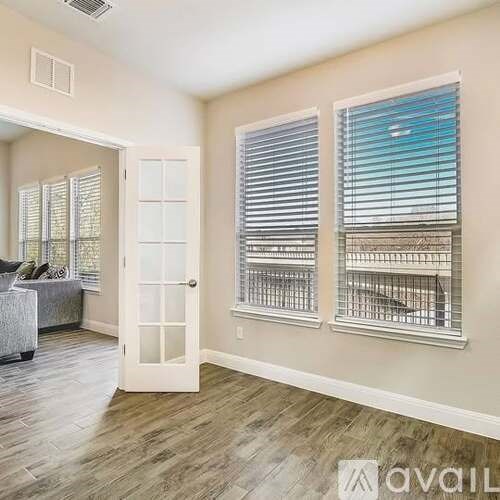 A room with a couch, a door, and a window with blinds.