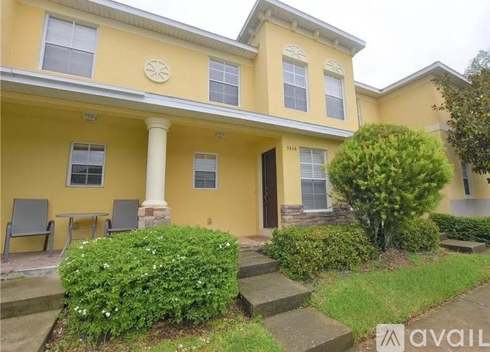 A yellow house with a front porch and a tree in the front yard.