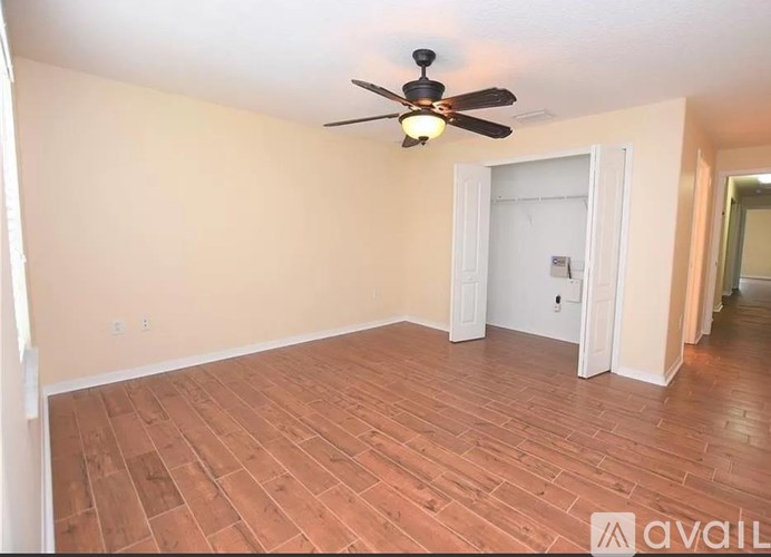 A room with a ceiling fan and wooden flooring.