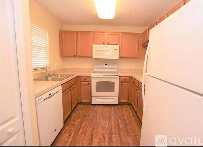 A kitchen with wooden floors and white appliances.