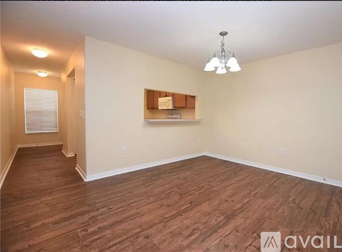 A room with wooden flooring and a chandelier hanging from the ceiling.