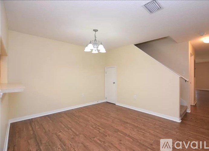 A room with wooden flooring and a chandelier hanging from the ceiling.