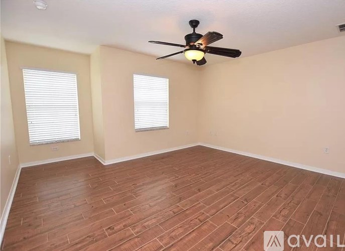 A room with a ceiling fan and wooden flooring.