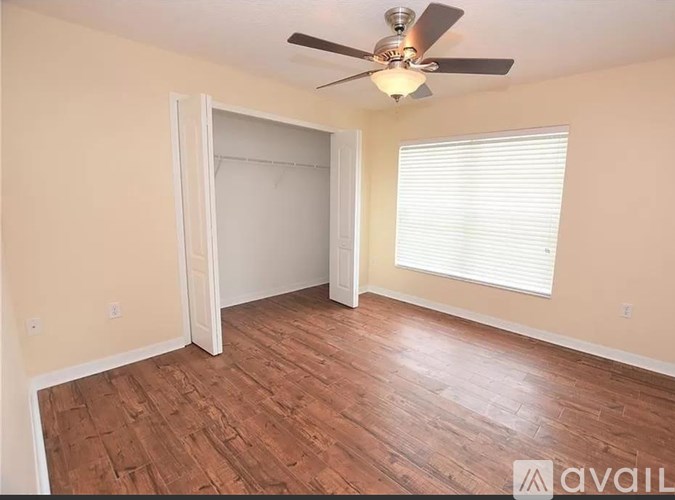 A room with a ceiling fan and wooden flooring.