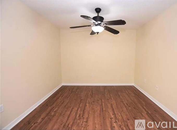 Empty room with wooden floor and ceiling fan.