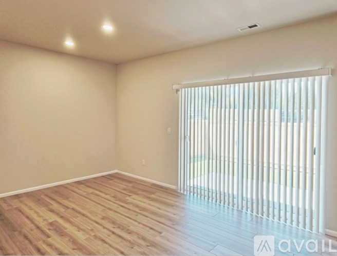 A room with wooden flooring and a window with blinds.