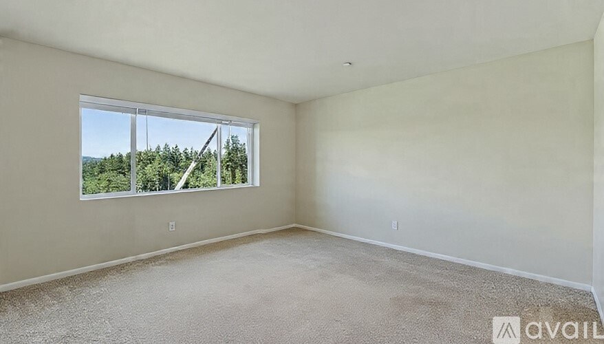 A room with a large window overlooking a forest.