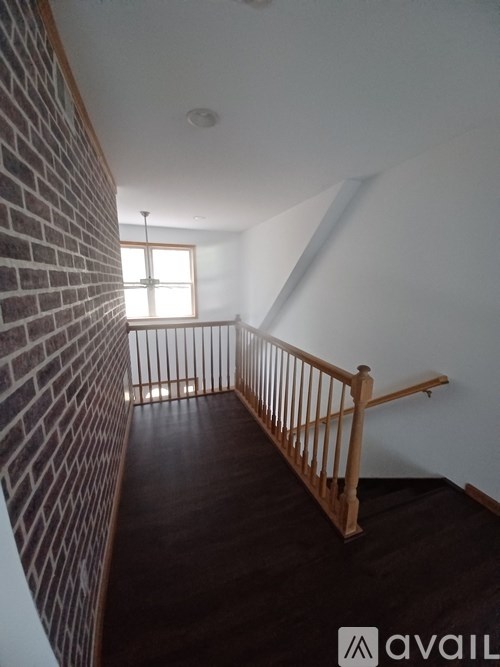 A room with a wooden staircase and a brick wall.