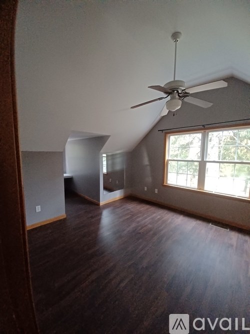 A room with a ceiling fan and wooden floors.