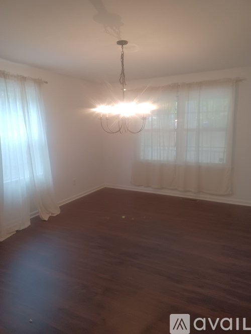 A room with a chandelier and a window with curtains.