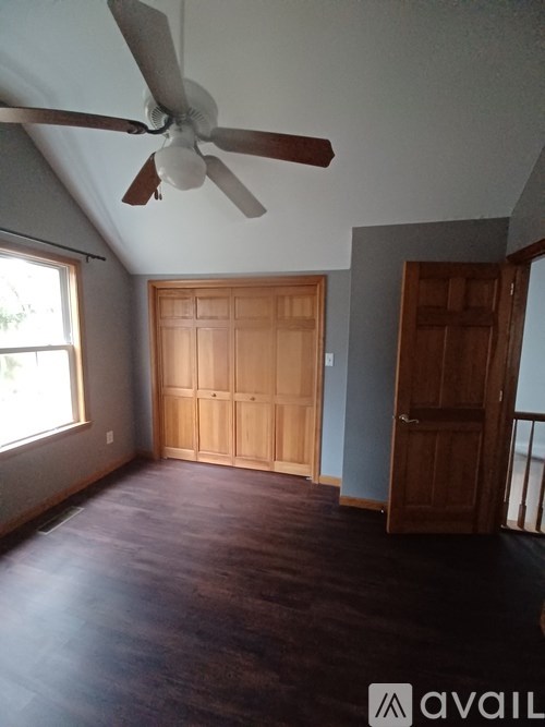 A room with a ceiling fan and a large wooden door.