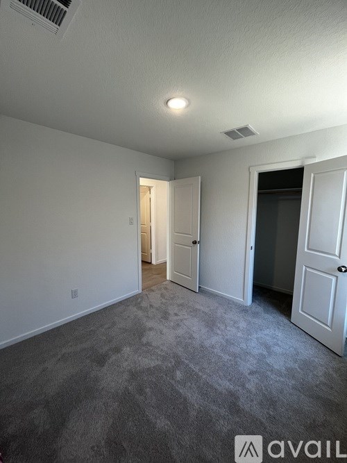 A room with a carpeted floor and two doors.