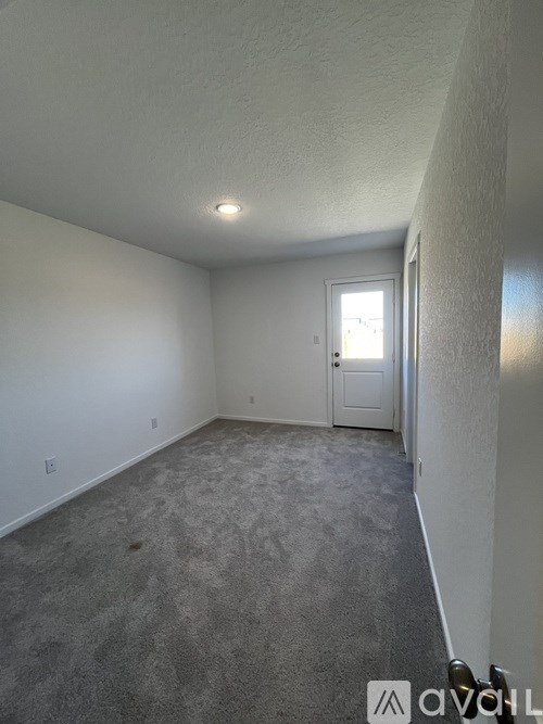 A room with a carpeted floor and a door leading to another room.