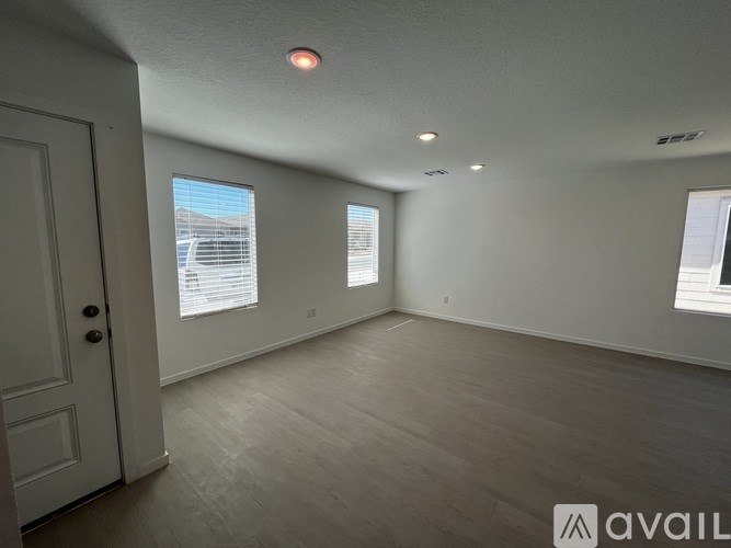A room with a white door and two windows with blinds.