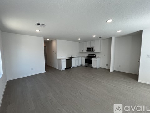 A spacious living room with a kitchenette in the background.