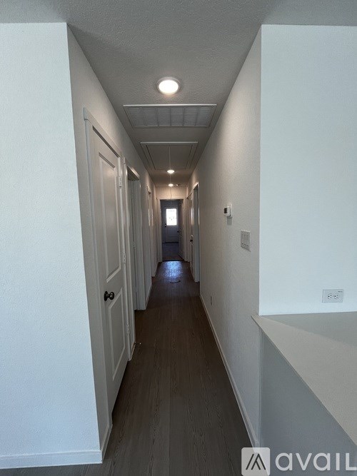 A long hallway with white walls and wood flooring.